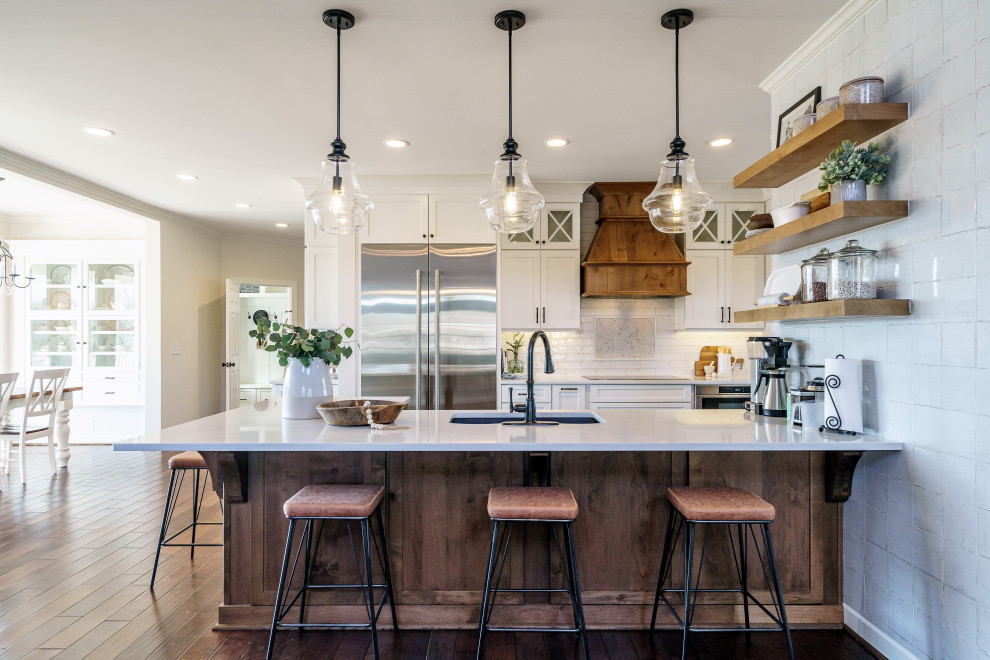 Example of a huge country l-shaped medium tone wood floor and brown floor open concept kitchen design in Raleigh with an undermount sink, shaker cabinets, white cabinets, quartzite countertops, white backsplash, ceramic backsplash, stainless steel appliances, an island and white countertops