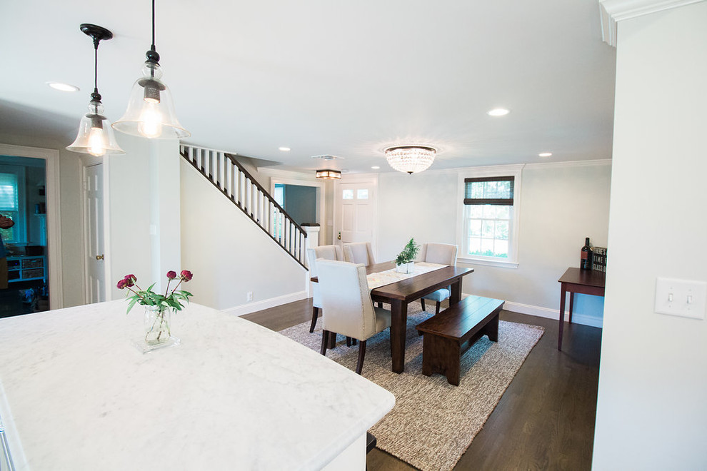 Inspiration for a mid-sized transitional l-shaped dark wood floor and brown floor eat-in kitchen remodel in Boston with a farmhouse sink, shaker cabinets, white cabinets, marble countertops, gray backsplash, subway tile backsplash, stainless steel appliances and an island