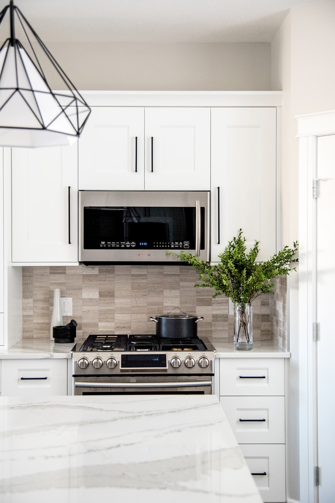 Mid-sized transitional l-shaped kitchen pantry in Other with an undermount sink, shaker cabinets, white cabinets, quartzite benchtops, beige splashback, limestone splashback, stainless steel appliances, ceramic floors, with island and grey floor.