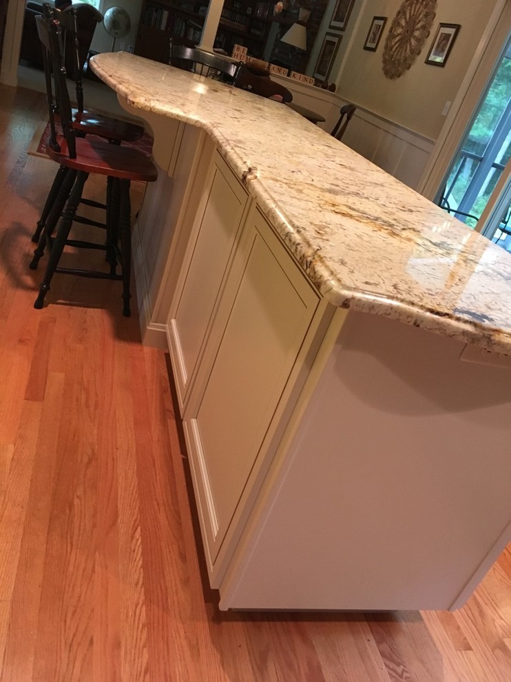 Transitional u-shaped light wood floor eat-in kitchen photo in Boston with an undermount sink, raised-panel cabinets, granite countertops, subway tile backsplash, stainless steel appliances and an island