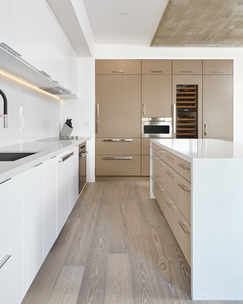 Photo of a large modern l-shaped eat-in kitchen in Toronto with an undermount sink, flat-panel cabinets, white cabinets, quartz benchtops, grey splashback, stone slab splashback, panelled appliances, medium hardwood floors, with island and brown floor.