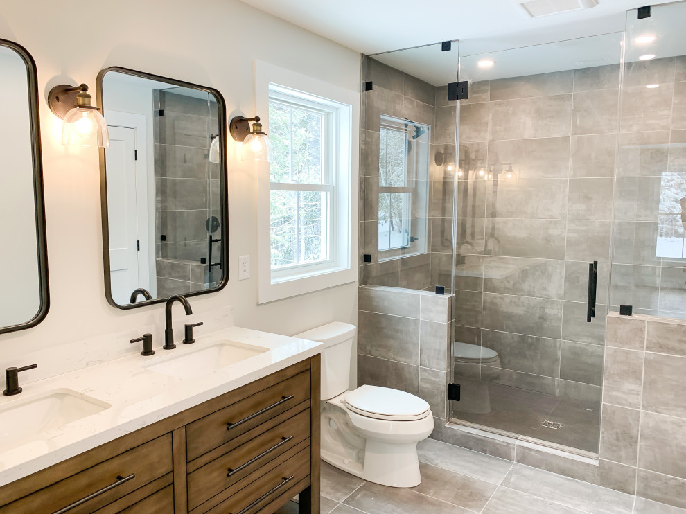 Inspiration for a large arts and crafts master bathroom in Boston with furniture-like cabinets, medium wood cabinets, a double shower, a two-piece toilet, gray tile, ceramic tile, white walls, ceramic floors, grey floor, a hinged shower door, white benchtops, a double vanity and a freestanding vanity.