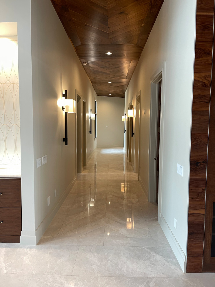 Foto di un ingresso o corridoio moderno con pareti bianche, pavimento in marmo, pavimento bianco e soffitto in legno