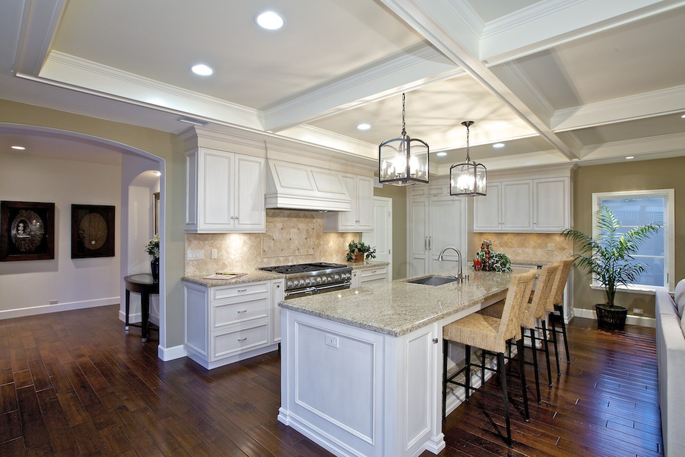Large traditional single-wall eat-in kitchen in San Diego with an undermount sink, beaded inset cabinets, white cabinets, granite benchtops, beige splashback, stone tile splashback, panelled appliances, dark hardwood floors, with island and brown floor.