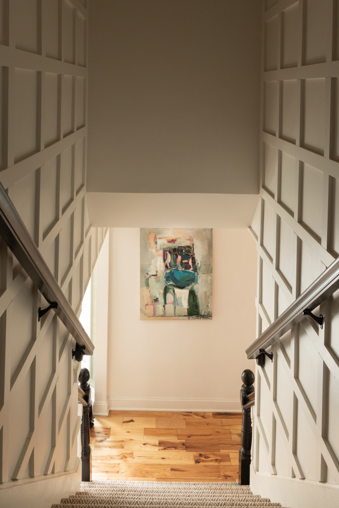 На фото: прямая лестница с ступенями с ковровым покрытием, ковровыми подступенками, деревянными перилами и панелями на стенах с