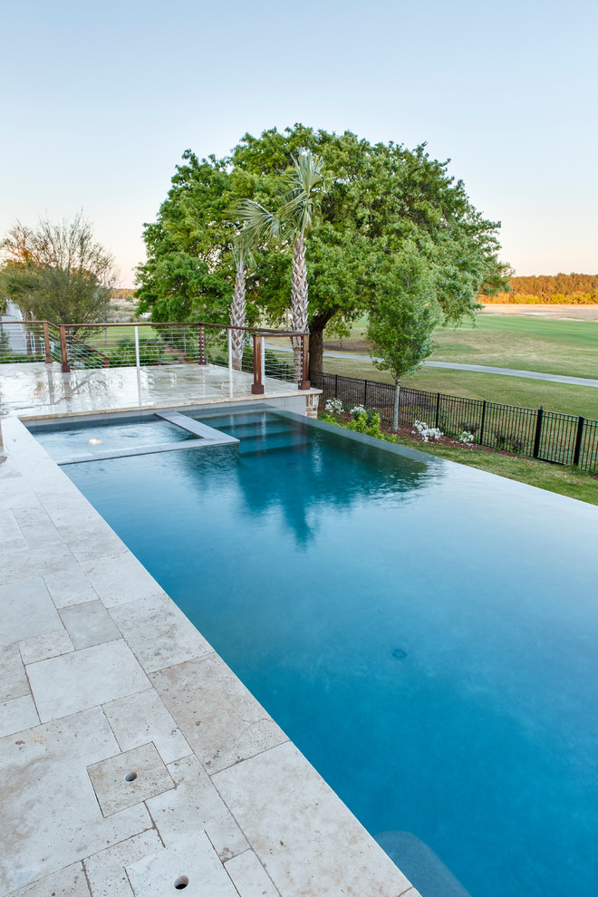 This is an example of a mid-sized contemporary backyard rectangular infinity pool in Charleston with a hot tub and natural stone pavers.