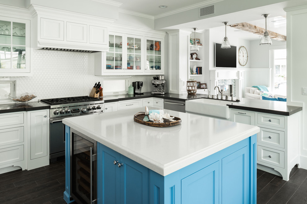 Large beach style u-shaped kitchen in Orange County with a farmhouse sink, white cabinets, white splashback, stainless steel appliances, with island and shaker cabinets.