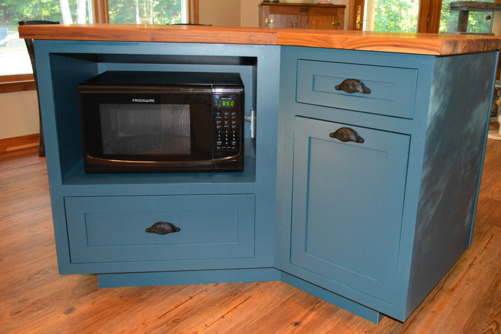 Eat-in kitchen - small transitional u-shaped medium tone wood floor and brown floor eat-in kitchen idea with a farmhouse sink, recessed-panel cabinets, white cabinets, wood countertops, white backsplash, ceramic backsplash, black appliances, an island and brown countertops