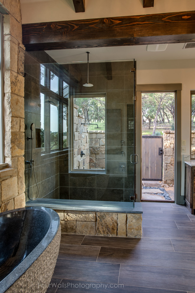 This is an example of a country 3/4 bathroom in Austin with open cabinets, medium wood cabinets, a freestanding tub, an alcove shower, a one-piece toilet, beige walls, medium hardwood floors, an integrated sink and wood benchtops.