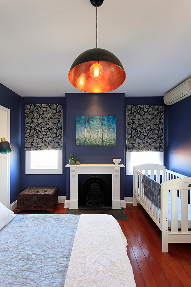 На фото: хозяйская спальня среднего размера в стиле неоклассика (современная классика) с синими стенами, паркетным полом среднего тона, стандартным камином, фасадом камина из дерева и коричневым полом с