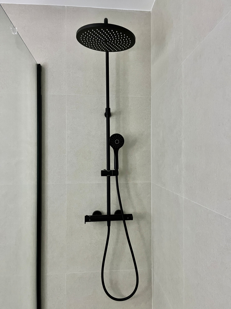 Diseño de aseo a medida minimalista grande con armarios con paneles lisos, puertas de armario grises, suelo de madera clara, suelo marrón, bandeja, sanitario de una pieza, baldosas y/o azulejos azules, baldosas y/o azulejos de cerámica, paredes grises, lavabo sobreencimera, encimera de acrílico y encimeras blancas