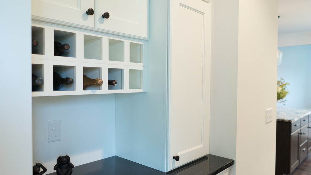 Example of a mid-sized transitional l-shaped dark wood floor open concept kitchen design with an undermount sink, shaker cabinets, white cabinets, granite countertops, gray backsplash, stainless steel appliances and an island