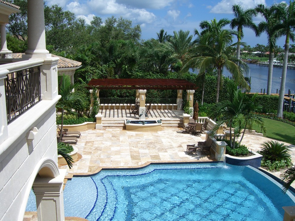 Photo of a large traditional backyard custom-shaped natural pool in Miami with concrete slab.