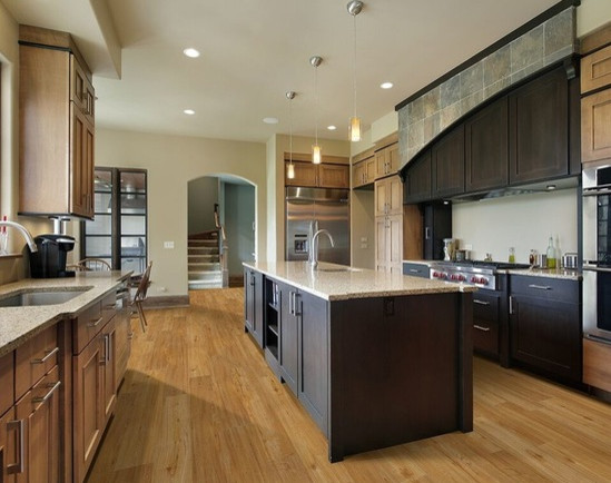 Enclosed kitchen - huge transitional l-shaped light wood floor enclosed kitchen idea in Jackson with an undermount sink, shaker cabinets, medium tone wood cabinets, granite countertops, beige backsplash, stainless steel appliances and an island