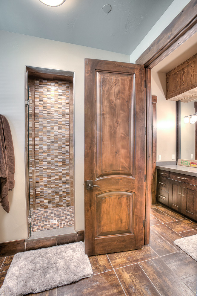 Photo of a mid-sized country 3/4 bathroom in Denver with shaker cabinets, dark wood cabinets, an alcove shower, a two-piece toilet, multi-coloured tile, matchstick tile, beige walls, slate floors, an undermount sink and solid surface benchtops.