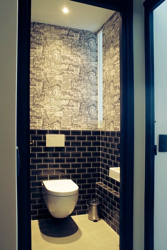 Inspiration for a mid-sized contemporary powder room in Paris with a wall-mount toilet, black tile, beige tile and subway tile.