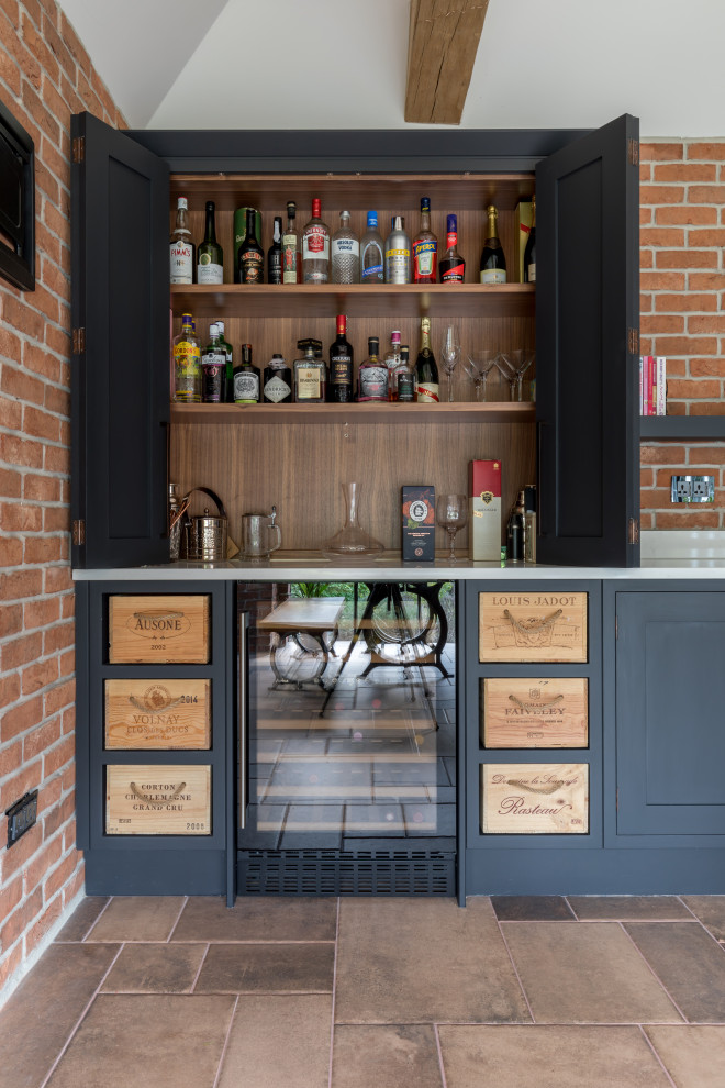 Imagen de bar en casa en L urbano de tamaño medio con puertas de armario azules, encimera de acrílico y encimeras blancas