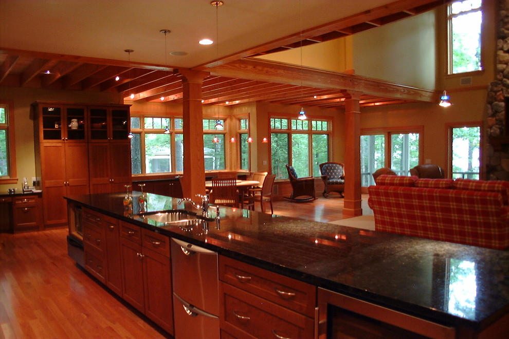 Example of a mountain style galley medium tone wood floor open concept kitchen design with a double-bowl sink, medium tone wood cabinets, granite countertops, stainless steel appliances and a peninsula
