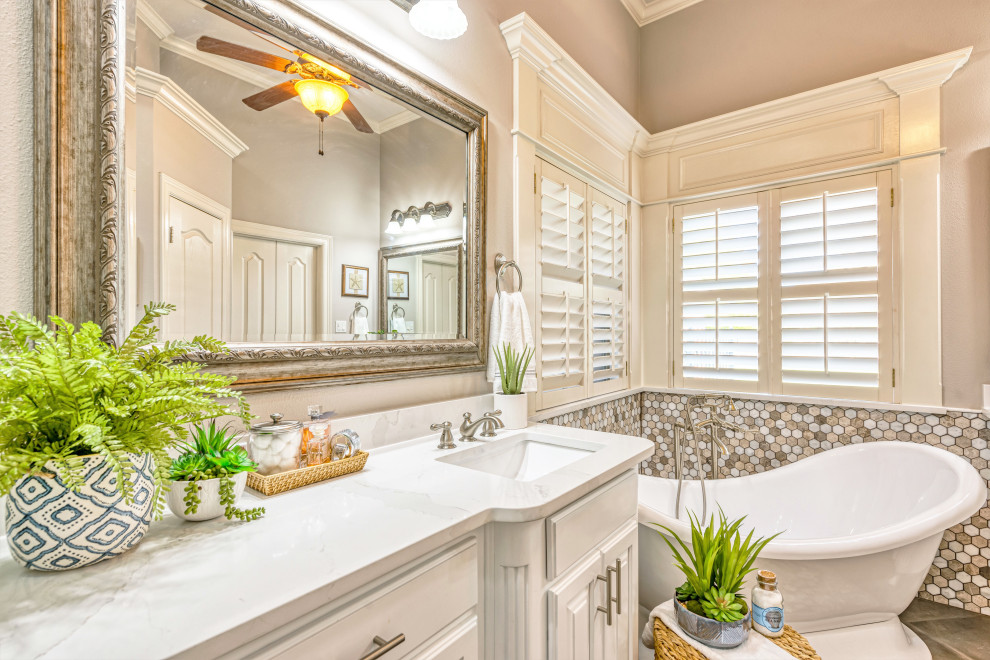 Inspiration for a mid-sized transitional master beige tile and porcelain tile porcelain tile and gray floor freestanding bathtub remodel with raised-panel cabinets, white cabinets, a one-piece toilet, beige walls, an undermount sink, quartzite countertops, a hinged shower door and white countertops