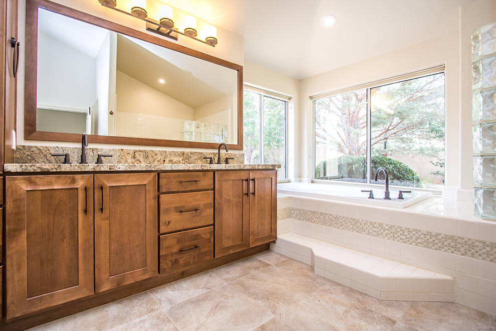 Inspiration for a large transitional master white tile and ceramic tile ceramic tile and beige floor drop-in bathtub remodel in Phoenix with shaker cabinets, medium tone wood cabinets, beige walls, an undermount sink, granite countertops and a hinged shower door