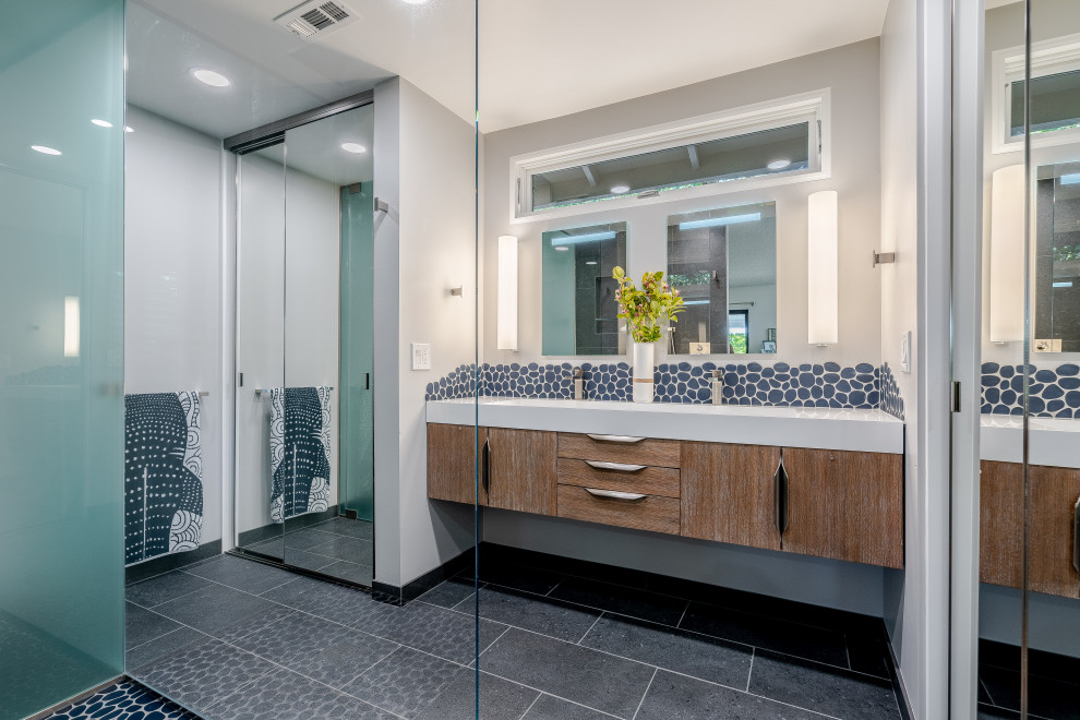 Foto de cuarto de baño doble y flotante contemporáneo con armarios con paneles lisos, puertas de armario de madera oscura, paredes grises, suelo gris, encimeras blancas y espejo con luz