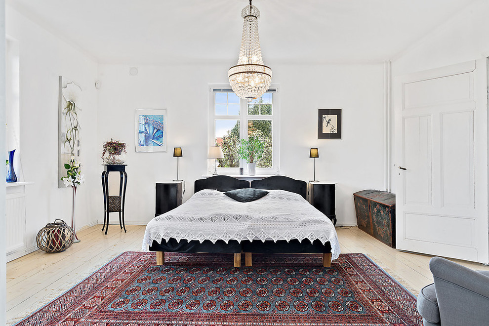 Large traditional master bedroom in Malmo with white walls, light hardwood floors and no fireplace.