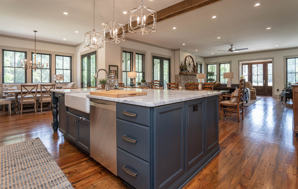 This is an example of a country open plan kitchen in Atlanta with a farmhouse sink, recessed-panel cabinets, blue cabinets, stainless steel appliances, medium hardwood floors, with island, brown floor and grey benchtop.