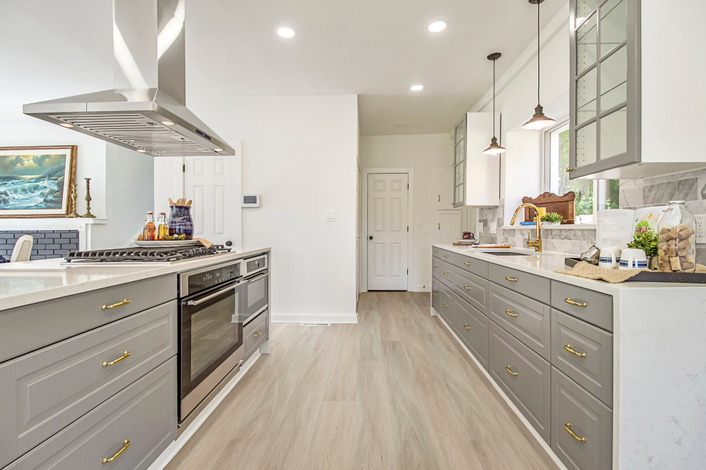 This is an example of a modern galley kitchen in Los Angeles with a drop-in sink, shaker cabinets, grey cabinets, quartzite benchtops, grey splashback, ceramic splashback, stainless steel appliances, vinyl floors, no island, beige floor and white benchtop.