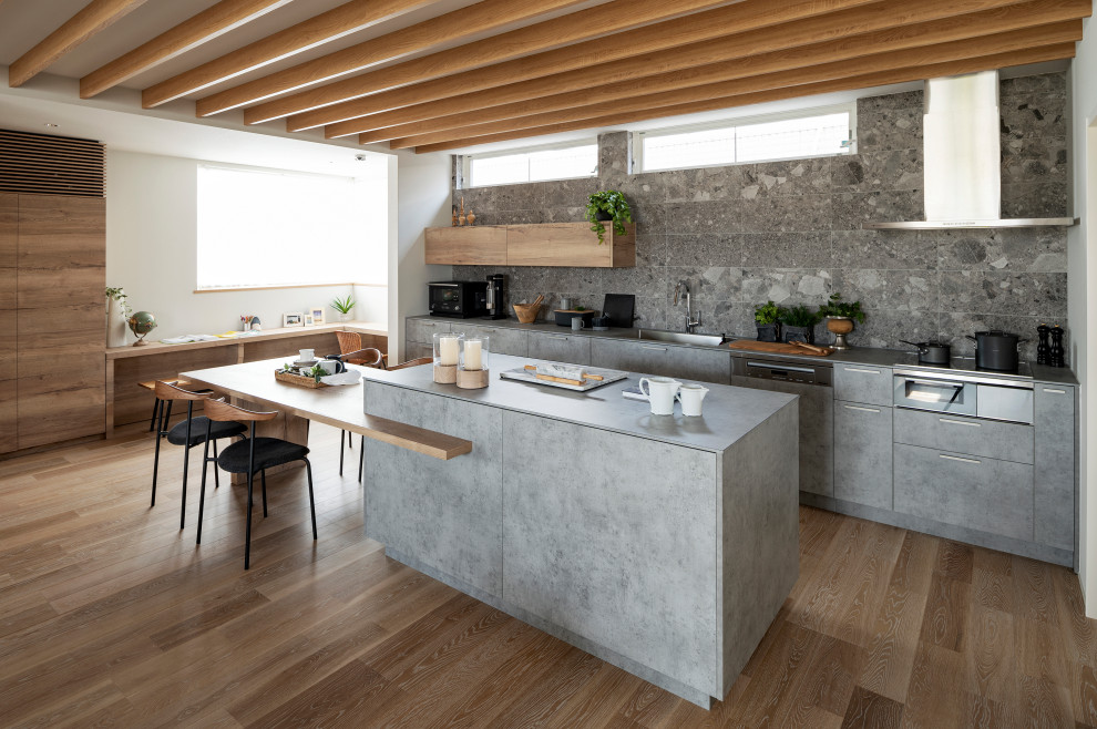 Foto på ett funkis grå linjärt kök med öppen planlösning, med en undermonterad diskho, luckor med profilerade fronter, grå skåp, laminatbänkskiva, grått stänkskydd, stänkskydd i keramik, svarta vitvaror, mellanmörkt trägolv, en köksö och beiget golv
