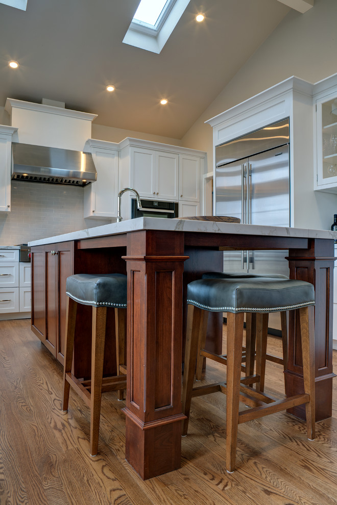 Inspiration for a large traditional u-shaped open plan kitchen in San Francisco with an undermount sink, recessed-panel cabinets, white cabinets, quartz benchtops, white splashback, stainless steel appliances, medium hardwood floors, with island and brown floor.