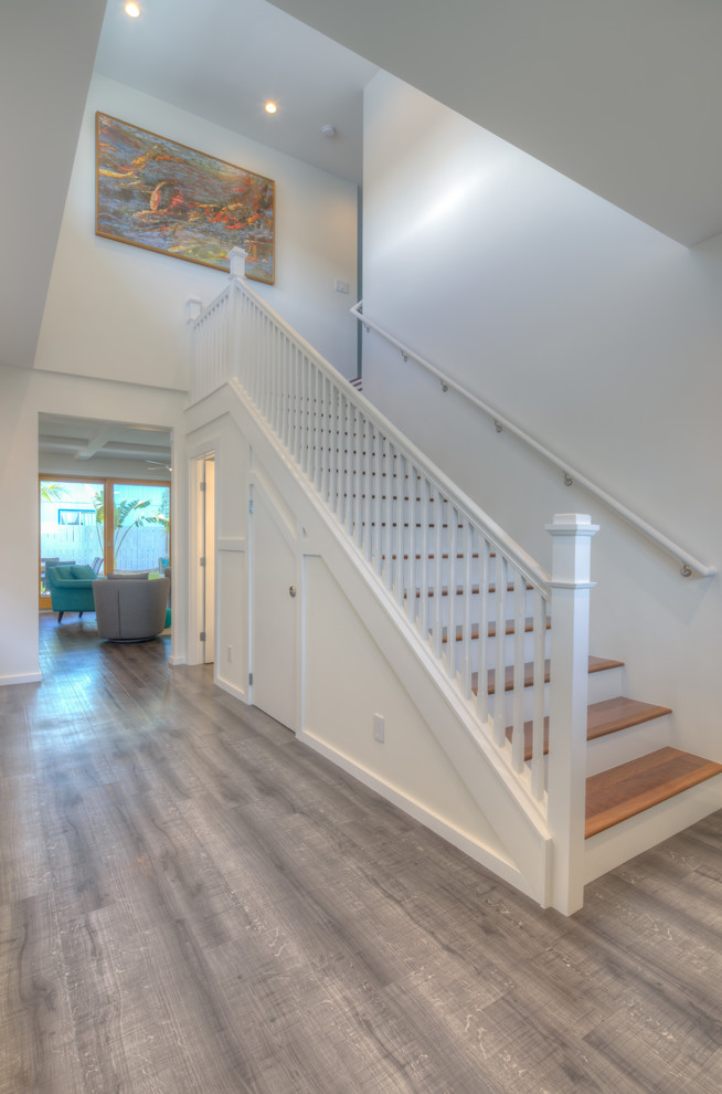 This is an example of a large transitional foyer in Hawaii with white walls, vinyl floors, a double front door, a light wood front door and grey floor.