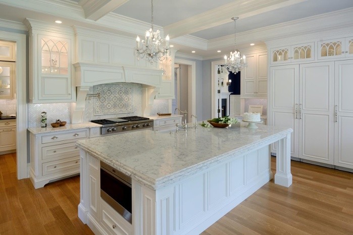 Photo of a large traditional l-shaped eat-in kitchen in Boston with raised-panel cabinets, white cabinets, white appliances, light hardwood floors and with island.