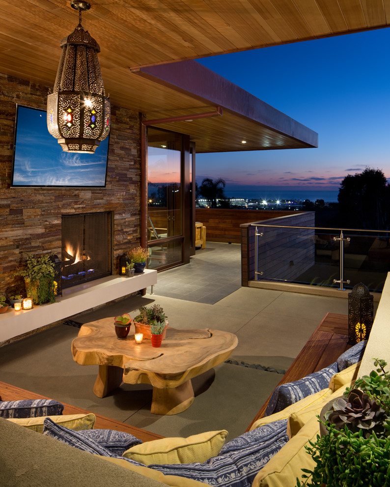 Asian deck in San Diego with a fire feature and a roof extension.