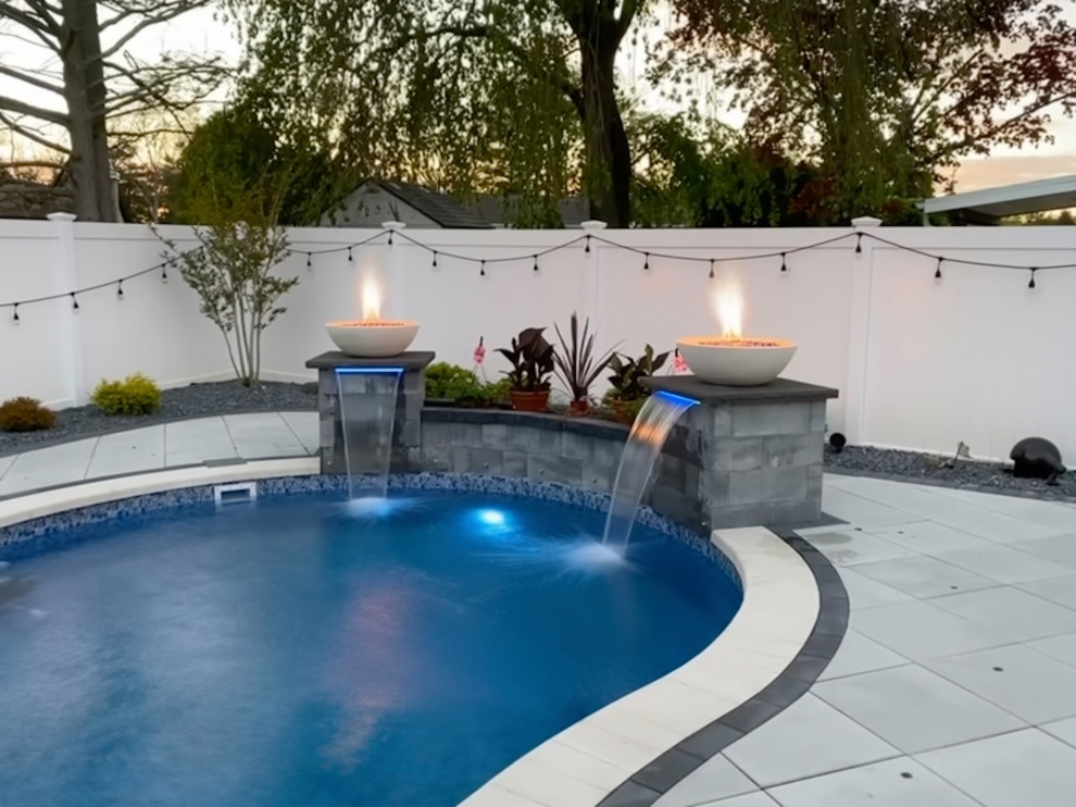 This is an example of a large modern backyard kidney-shaped lap pool in New York with a water feature and concrete pavers.