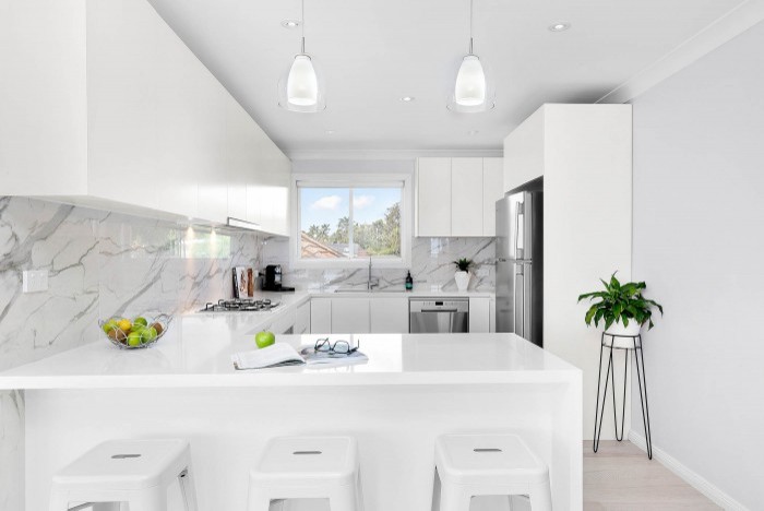 Inspiration for a large beach style l-shaped eat-in kitchen in Sydney with a double-bowl sink, flat-panel cabinets, white cabinets, quartz benchtops, multi-coloured splashback, ceramic splashback, stainless steel appliances, light hardwood floors, no island and multi-coloured floor.