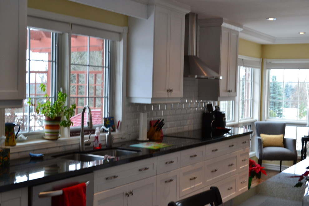 Example of a large transitional galley medium tone wood floor eat-in kitchen design in Toronto with a double-bowl sink, shaker cabinets, white cabinets, granite countertops, white backsplash, subway tile backsplash, stainless steel appliances and an island