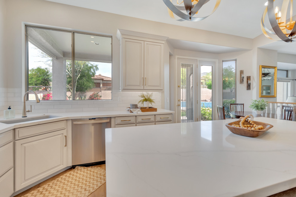 Example of a mid-sized transitional u-shaped eat-in kitchen design in Phoenix with an undermount sink, raised-panel cabinets, gray cabinets, quartz countertops, white backsplash, subway tile backsplash, stainless steel appliances, an island and white countertops