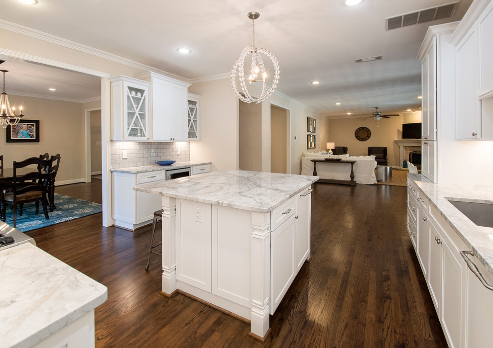 Example of a large transitional u-shaped medium tone wood floor open concept kitchen design in Dallas with an undermount sink, shaker cabinets, white cabinets, quartz countertops, white backsplash, porcelain backsplash, stainless steel appliances and an island