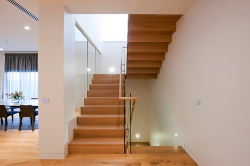 Photo of a large contemporary wood u-shaped staircase in Melbourne with wood risers.
