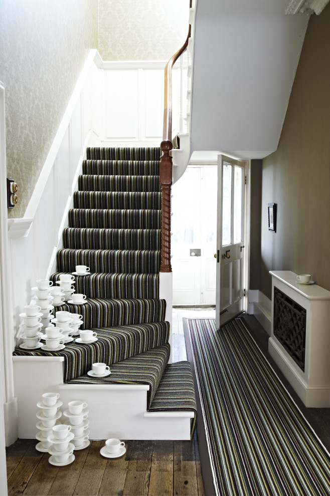 Large modern carpeted l-shaped staircase in Other with carpet risers and wood railing.