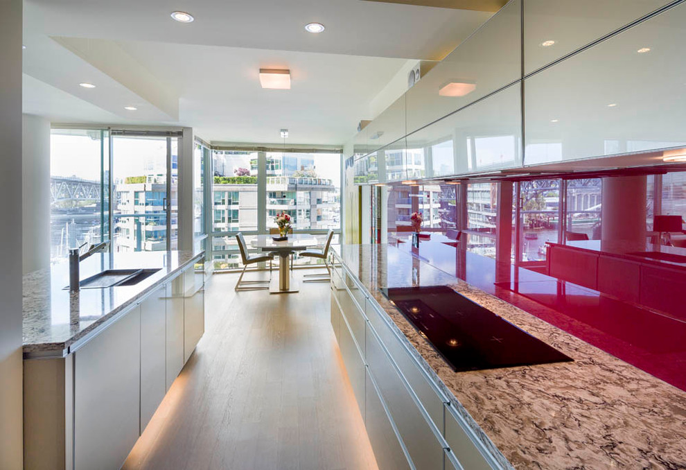 Inspiration for a mid-sized modern galley open plan kitchen in Vancouver with red splashback, glass sheet splashback, light hardwood floors, beige cabinets, an undermount sink, flat-panel cabinets, granite benchtops, panelled appliances, no island and beige floor.