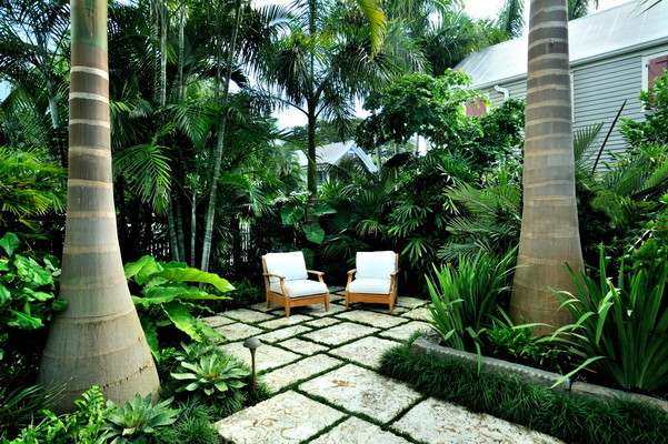 Photo of a mid-sized tropical side yard patio in Miami with natural stone pavers.