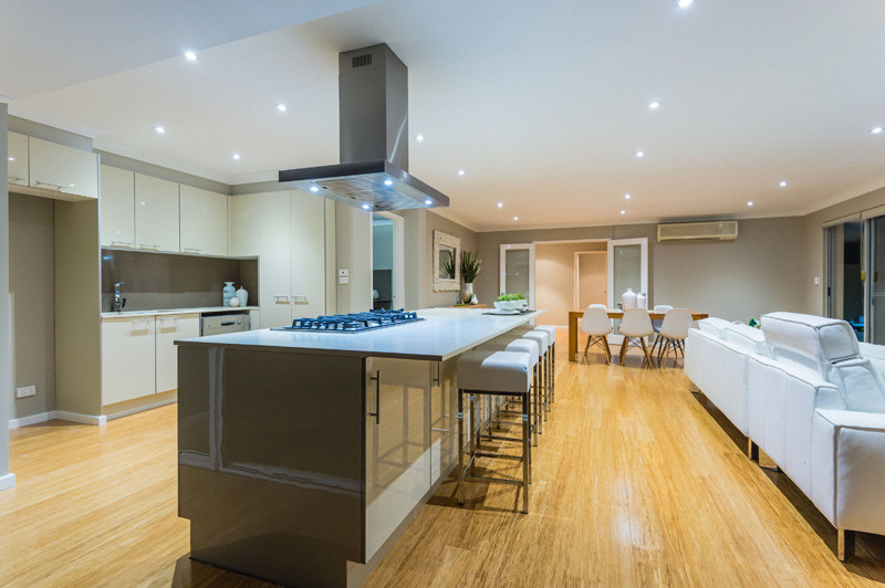 Inspiration for a large contemporary galley open plan kitchen in Perth with a double-bowl sink, beige cabinets, brown splashback, stainless steel appliances, bamboo floors, with island, brown floor, white benchtop, quartz benchtops, flat-panel cabinets and stone slab splashback.