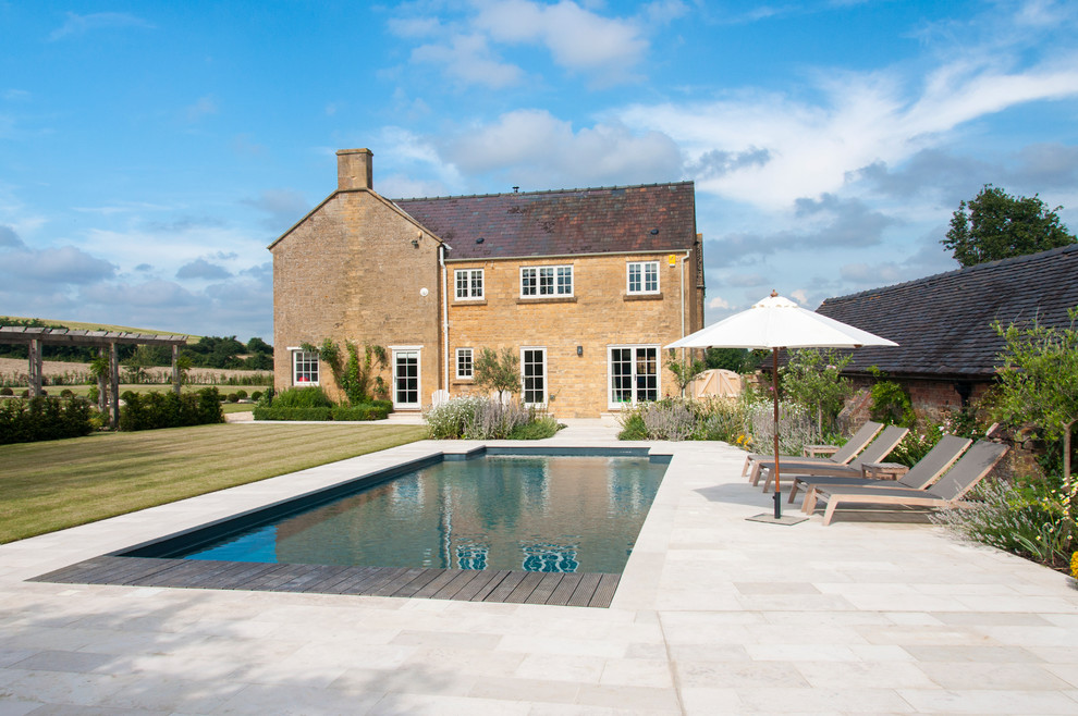 Mid-sized country backyard rectangular pool in Gloucestershire with concrete slab.