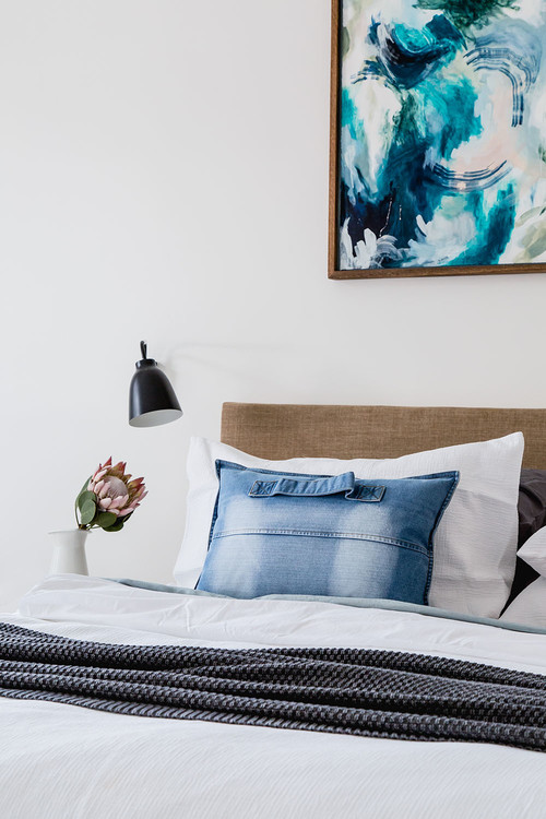 bed frame with cloth headboard below abstract painting