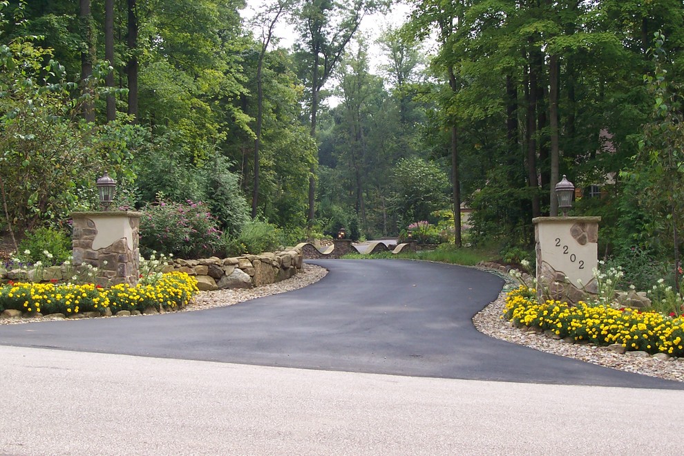 Photo of a large country front yard shaded driveway for winter in Cleveland with gravel.