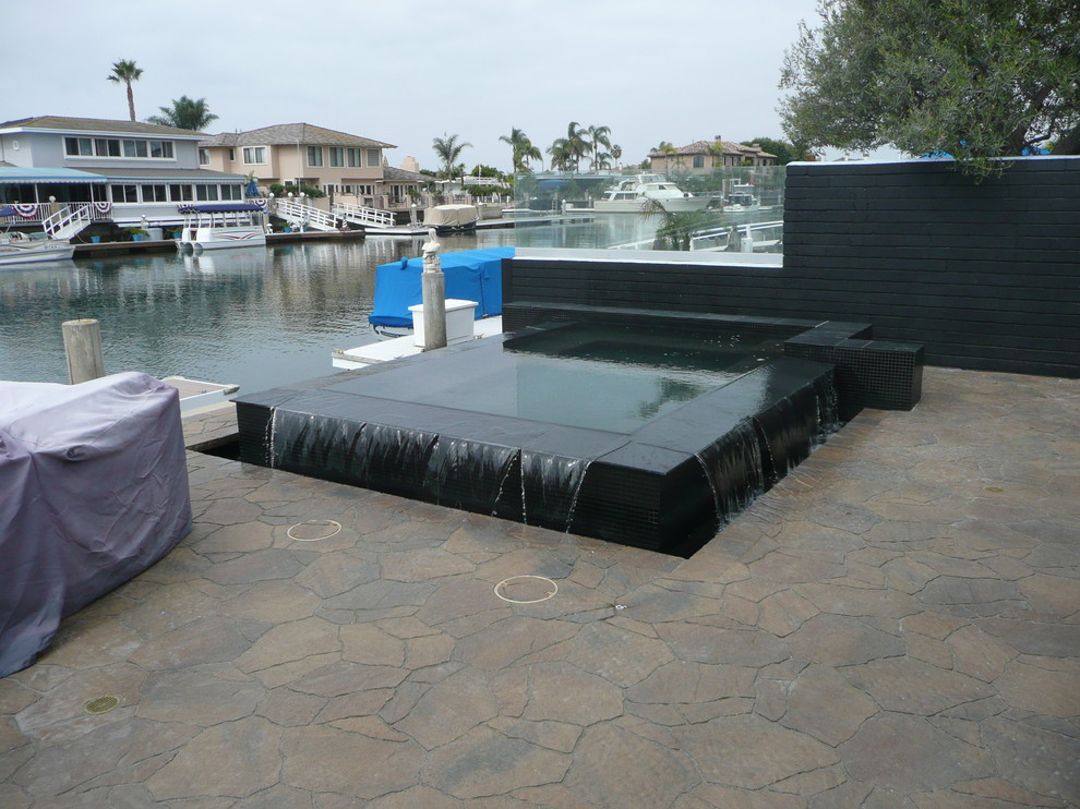 This is an example of a small modern backyard rectangular pool in Los Angeles with a hot tub and stamped concrete.