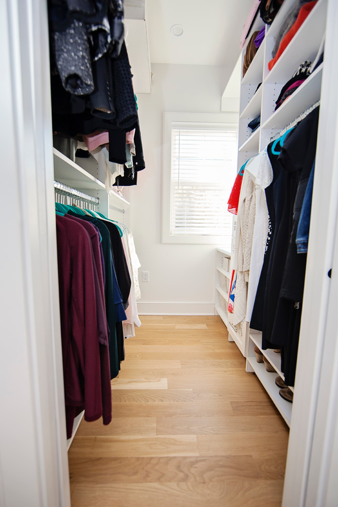 Mid-sized transitional walk-in wardrobe in New York with white cabinets and light hardwood floors.