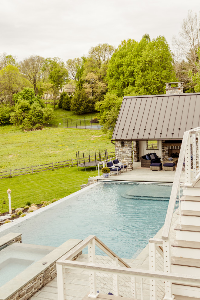 Idee per una grande piscina a sfioro infinito minimal rettangolare dietro casa con una dépendance a bordo piscina e pavimentazioni in pietra naturale