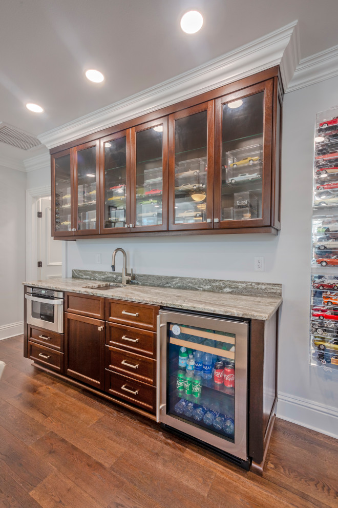 Home bar in Tampa with a submerged sink, beaded cabinets, dark wood cabinets, marble worktops, dark hardwood flooring, brown floors and multicoloured worktops.